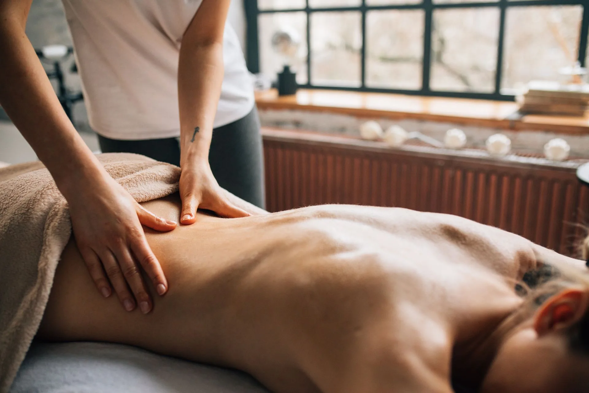 Therapist giving a back massage to a client in a warm, calm treatment room
